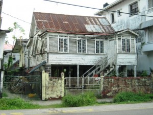 A dilapidated home with stained glass windows, decorative ventilation openings and Demerara shutters still intact