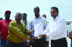 Sport Minister Dr Frank Anthony (right) hands over a signed contract to Office Manager of BK International Inc Egan Bazilio (left) in the presence of Permanent Secretary of the Sport Ministry, Alfred King (background)