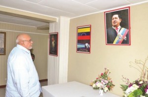 President Donald Ramotar solemnly looks at a portrait of Venezuelan President Hugo Chávez who died on Tuesday. The Guyanese head-of-state signed the book of  condolences at the Venezuelan embassy in Georgetown on Wednesday