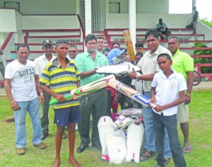 Club Secretary Ronald Goolghar (left) receives a quantity of cricket gear from Surenda Nauth of Nauth’s Motor Spares. Looking on are Sheik Mohamed (left) of Tiger Sports, club president Naim Chan (second left), well wishers and some participants of the academy