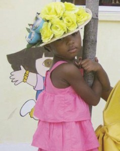 A shy Kiskadee student and her hat decorated beautifully with yellow flowers