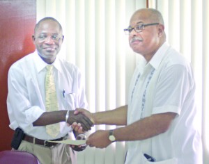 UG Vice Chancellor, Professor Jacob Opadeyi and Ohio University School of Media Arts and Studies Professor Emeritus, Dr Vibert Cambridge shake hands after signing the agreement