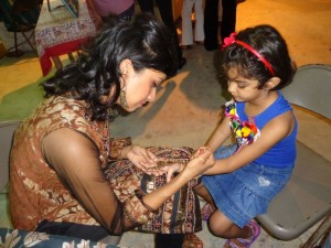 Being creative- One of the youth group's members (left) applying mehendi art to a child's hands at a recently held Phagwah Mela