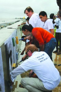 Canadian High Commissioner to Guyana David Devine (left), Minister of Education Priya Manickchand, and US Ambassador to Guyana Brent Hardt (far right) help with the posters at the seawall