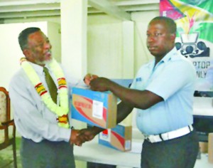 Prime Minister Hinds presenting a laptop to Ronald Thomas in Plaisance