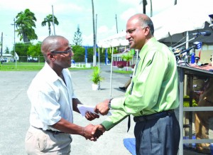 Crime Chief Seelall Persaud hands over a monetary award to one of the ranks for his outstanding performance 