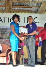 Blairmont champion worker Avril Patricia Spencer receives her certificate from a GuySuCo official