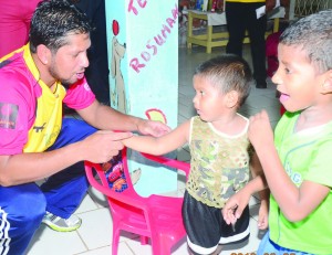 Guyana Amazon Warriors Captain Ramnaresh Sarwan tries to get the attention of this child during his team’s visit to the Convalescent Home on Tuesday