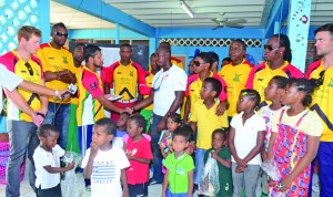 The coaching staff and players of the Guyana Amazon Warriors witness their captain Ramnaresh Sarwan making a financial contribution to the administrator of the Children's Convalescent Home, Erwin Enmore on Tuesday 