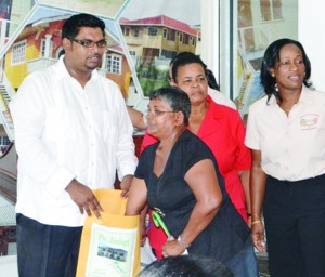 Guyana’s Housing and Water Minister Irfaan Ali holds the envelope as one applicant draws the number of her new house lot at Zeelugt, East Bank Essequibo