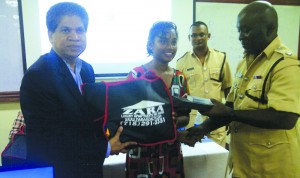 Zara Holding consultant Naresh Singh and Police G Division Commander Steven Mancell make presentations to Zamina Rasheed in the presence of a police officer 