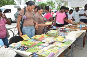 Guyanese browsing through the various books being distributed outside of the Education Ministry