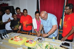 President Donald Ramotar sticking the Progressive Youth Organisation’s 61st anniversary cake with several members