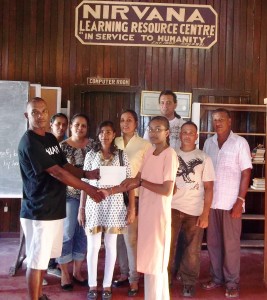 Abideen Shaw, committee member of Nirvana, presents the scholarship grant to Parmeshwari, while other members of Nirvana look on