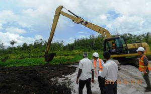 A Hymac in full operation removing the peat, as Transport and Public Works Minister Robeson Benn and CHEC engineers look on