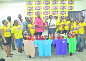 Managing Director of Guyana Beverage Company Robert Selman hands over the Busta Champions of Champions winner’s trophy to RHTY&SC, CEO/Secretary Hilbert Foster in the presence of other club officials and staff members of the beverage company (Photos: Rajiv Bisnauth)