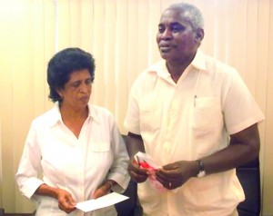 Public Works Minister Robeson Benn gives Phyllis Rahaman a token on behalf of his office