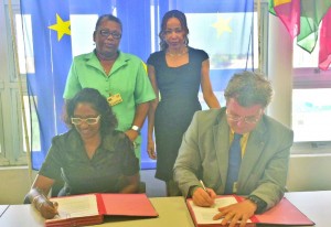 Ambassador Robert Kopecký (right) and ChildLink Programme Director Omattie Madray sign the grant contract while Forward Guyana Director Chantalle Haynes, (standing right) and Child Protection Agency Director Ann Greene look on