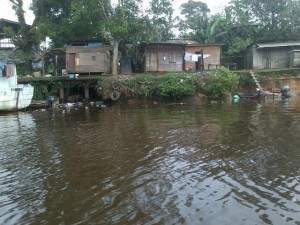 Several shacks with accompanying latrines along the river bank in Port Kaituma, North West District