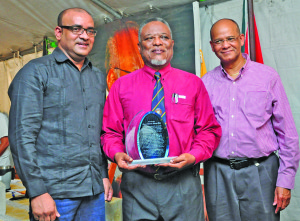 Prime Minister Samuel Hinds stands with Former President Bharrat Jagdeo and PPP/C General Secretary Clement Rohee moments after being recognised by the PYO at Red House, Kingston