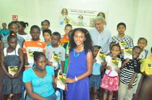 Anaya Willabus presents an autographed book to a fan in the presence of other children and Education Minister Rupert Roopnaraine 