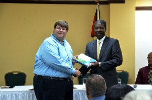 OAS Country Representative Jean Dormeus handing over a copy of the Secondary School Drug Prevalence Survey 2013 report to US Embassy Chargé d'Affaires Bryan Hunt