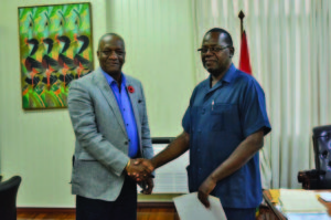 Retired Assistant Commissioner of Police, Winston Cosbert being presented with the Terms of Reference (TORs) by Minister of State, Joseph Harmon