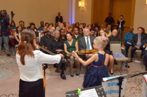 President David Granger and First Lady Mrs. Granger seem transported by the music as Ambassador Jernej Videtic's young daughter, Ms. Celeste Videtic performs 'Hark the Herald Angels' on violin. She is accompanied by professional violinist, Mrs. Chie Clarke.